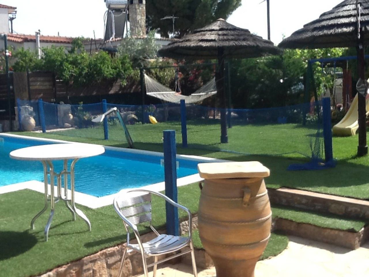 Una piscina con un'amaca, un tavolo e delle sedie.