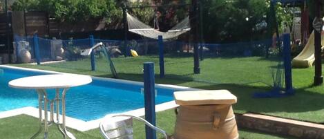 Una piscina con un'amaca, un tavolo e delle sedie.