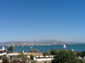 A coastal view with buildings, a clear sky, and sailboats on the water.