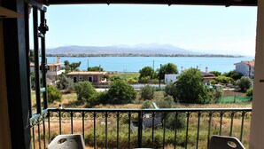 A balcony with a view of a lake, houses, and mountains in the distance.