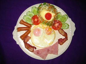 A plate of food with eggs, bacon, ham, and vegetables. - Grand Orchid Resort (Ko Chang)