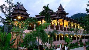 A traditional multi-tiered building with a pool and lounge chairs in the foreground. - Grand Orchid Resort (Ko Chang)