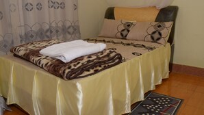 Una cama con una colcha de estampado de leopardo, una toalla blanca y almohadas estampadas.
