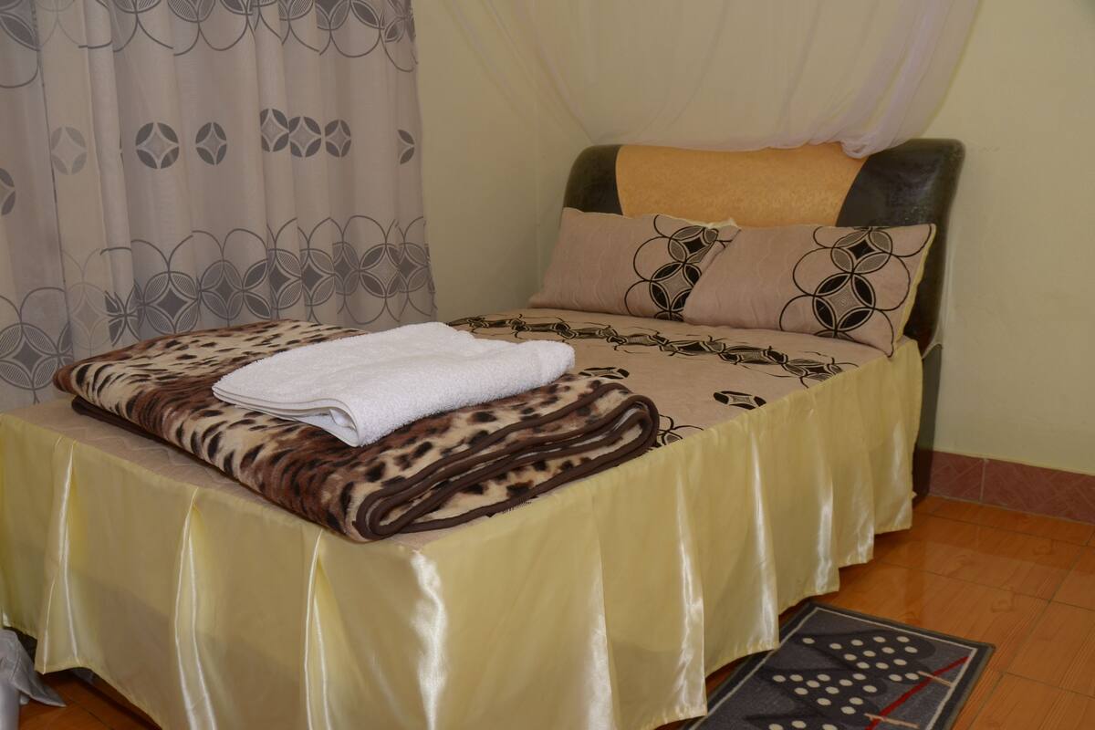 A bed with a leopard print bedspread, a white towel, and patterned pillows.