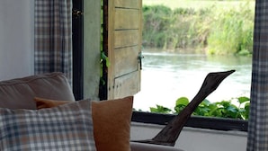 Ein Zimmer mit Flussblick, einer Holztür und einem Sofa mit karierten Kissen.