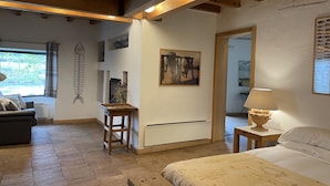 Ein gemütliches Zimmer mit einem Bett, einem Schreibtisch und einem Stuhl. Es gibt ein Fenster mit Vorhängen, eine Wand mit einem dekorativen Fischskelett und ein Gemälde.