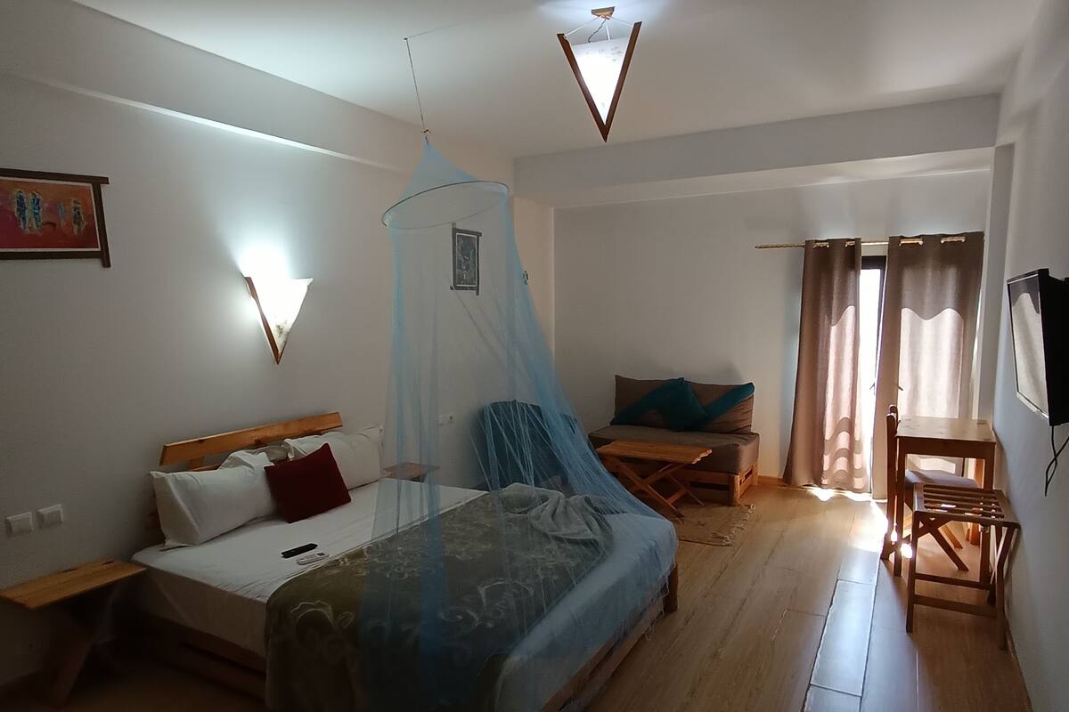 A bedroom with a bed, bedside table, and a small desk with a chair.