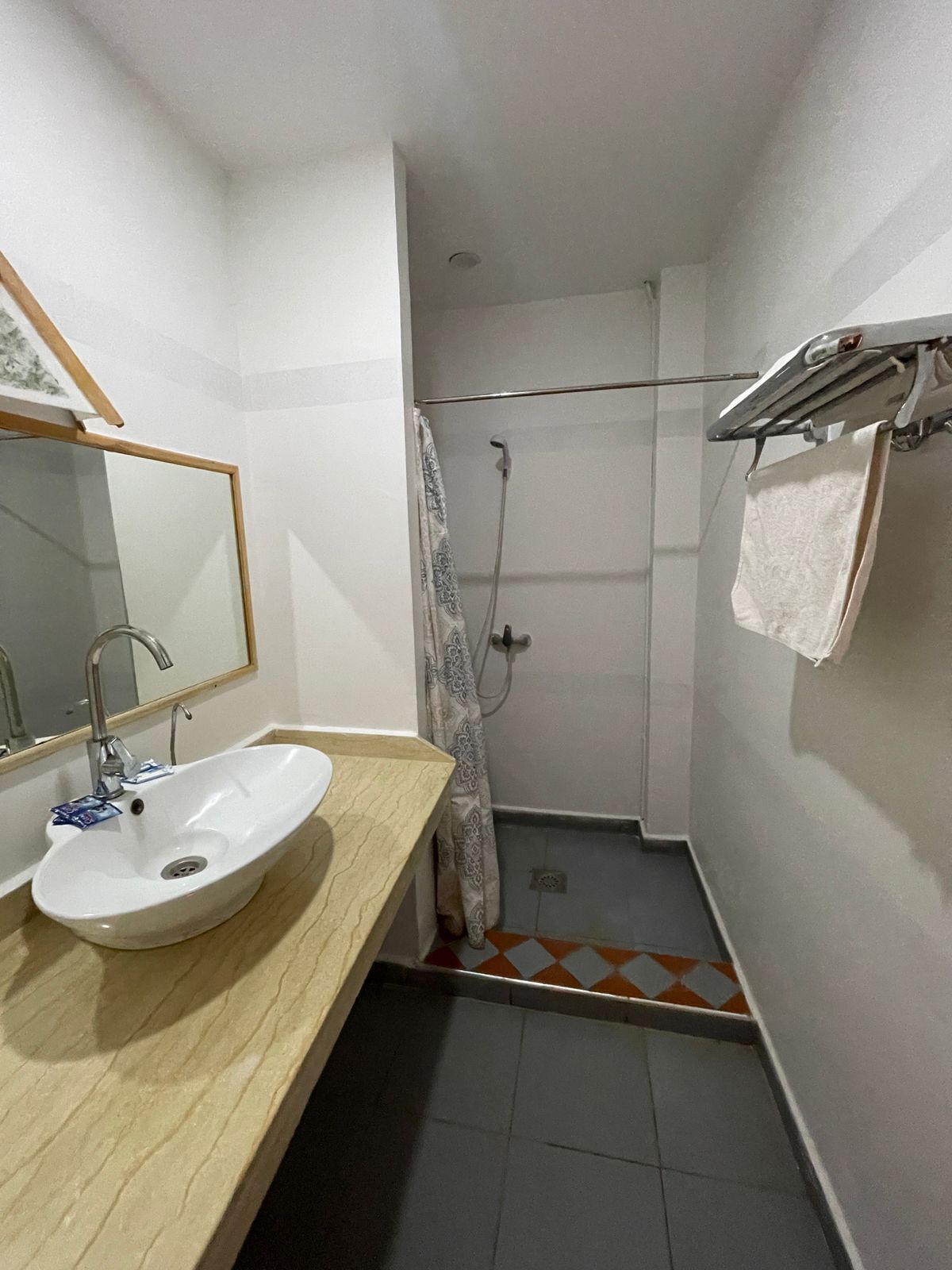 Un baño pequeño con lavamanos, espejo, ducha y toallero.