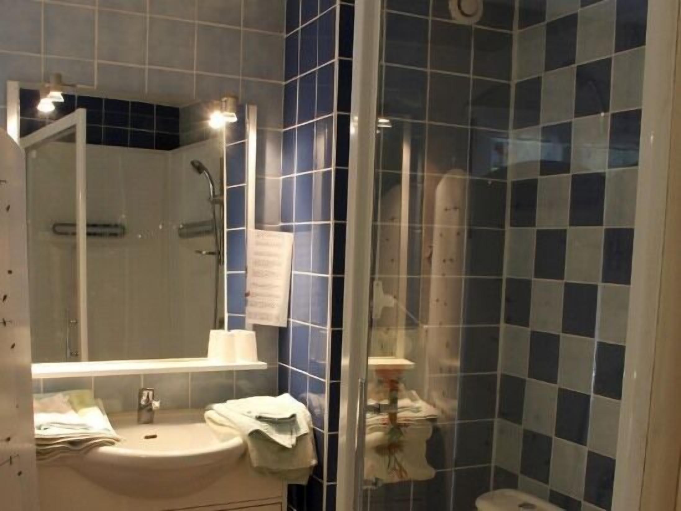 A bathroom with a sink, mirror, and shower area.