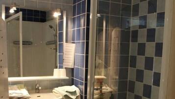 A bathroom with a sink, mirror, and shower area.