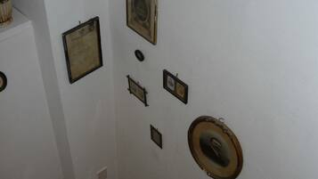 A wall with various framed items, including a large framed certificate, a smaller framed document, and a circular object with a central design.