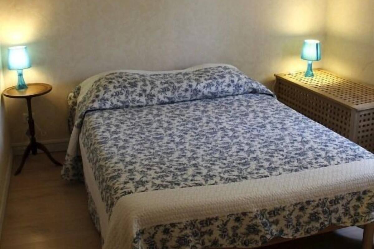 Une petite chambre à coucher, chaleureuse et accueillante, avec un lit, deux lampes de chevet et une table de nuit.