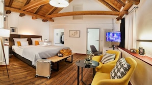 A spacious bedroom with a large bed, a desk, and a television.