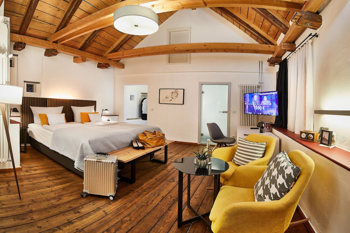 Een ruime slaapkamer met een groot bed, een bureau en een televisie.