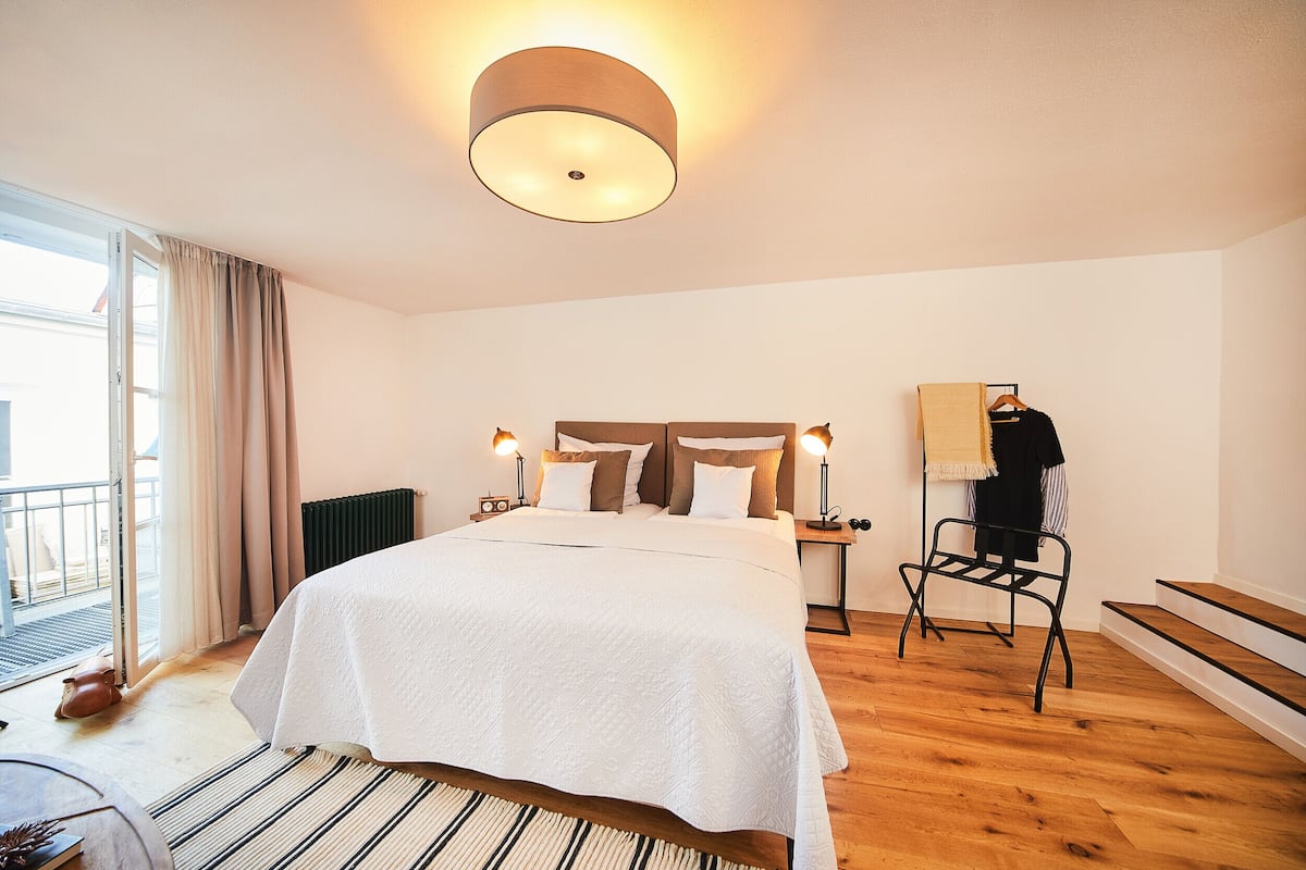Een hotelkamer met een bed, een stoel, een radiator en een raam met gordijnen.