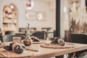 Una mesa de comedor con individuales tejidos, un jarrón con flores secas y una cesta de mimbre.