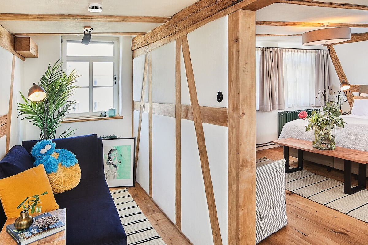 Een gezellige kamer met een bed, een houten bankje en een bank met kussens.