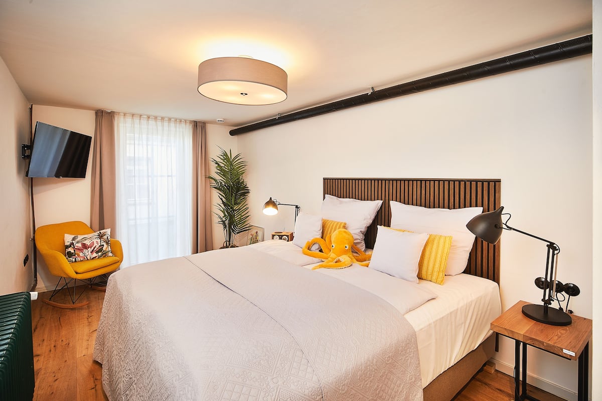 Hotelkamer met een groot bed, een aan de muur bevestigde televisie, een bureau met een lamp en een stoel.
