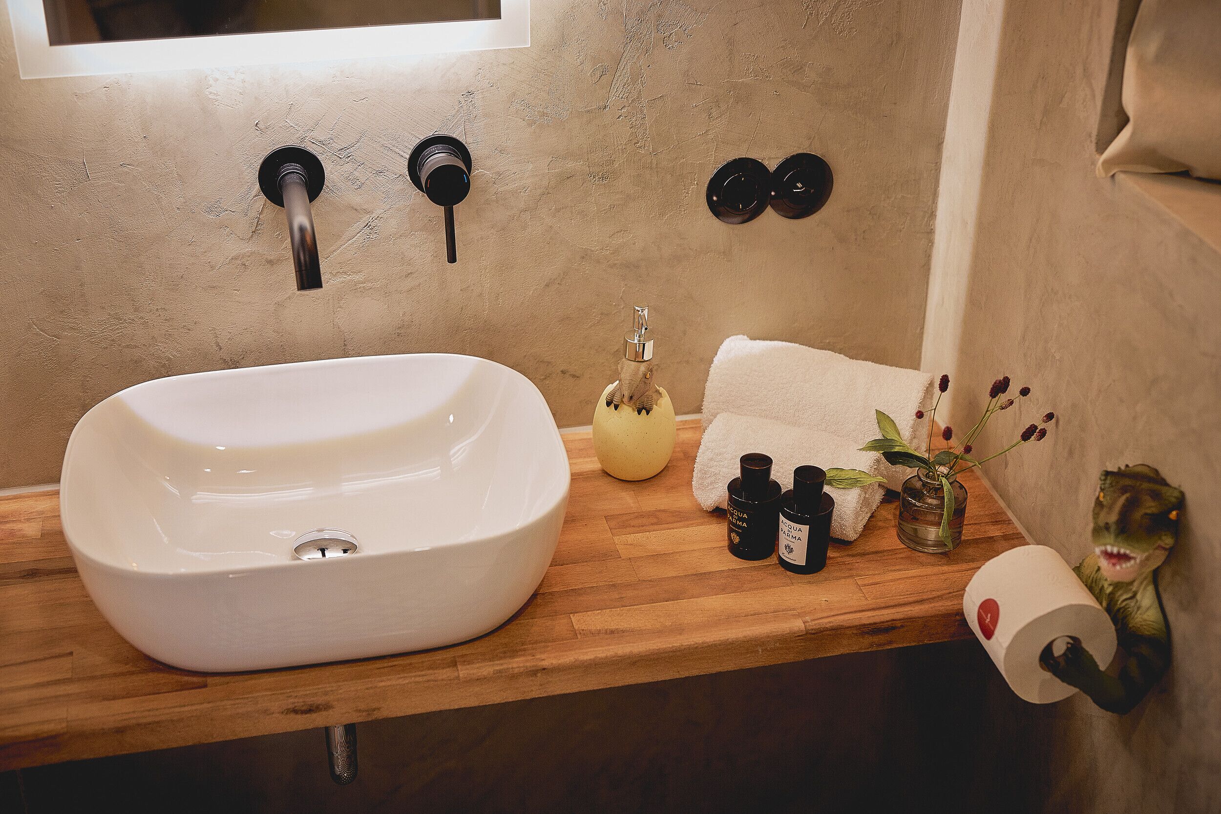 A bathroom with a white sink, wooden countertop, and a dinosaur decoration.