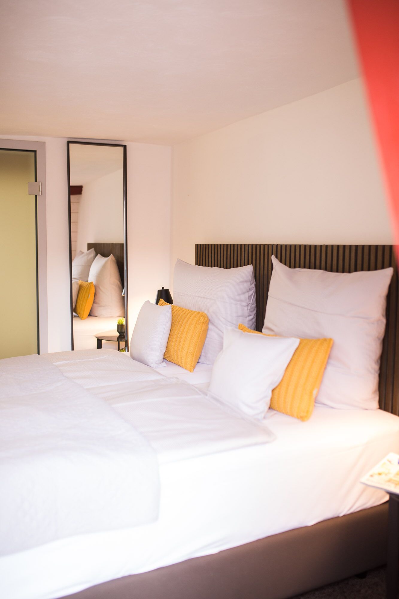 Una habitación de hotel con una cama grande, una mesita de noche y un espejo.