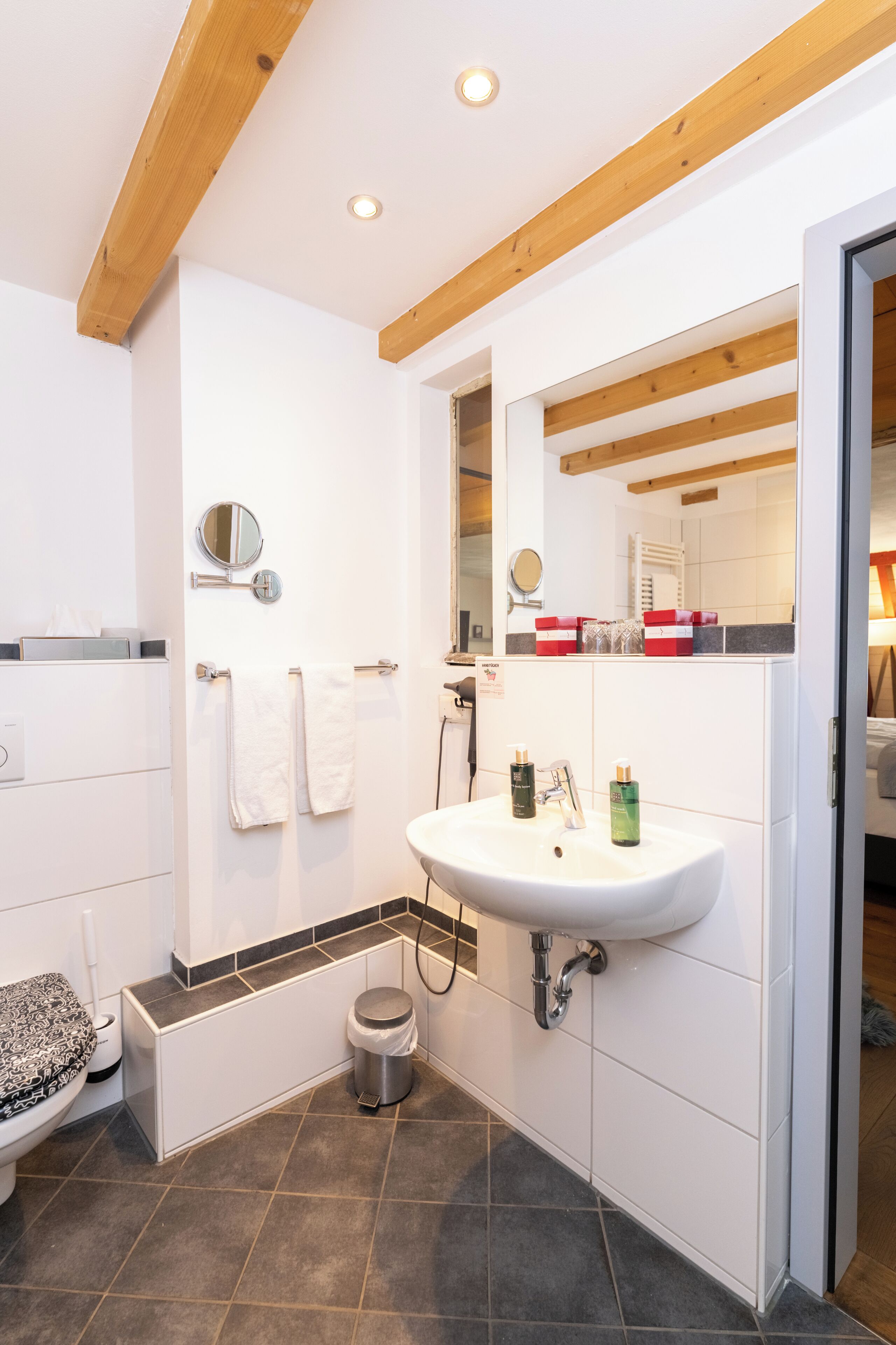Un baño moderno con lavamanos, espejo y toallero blancos.