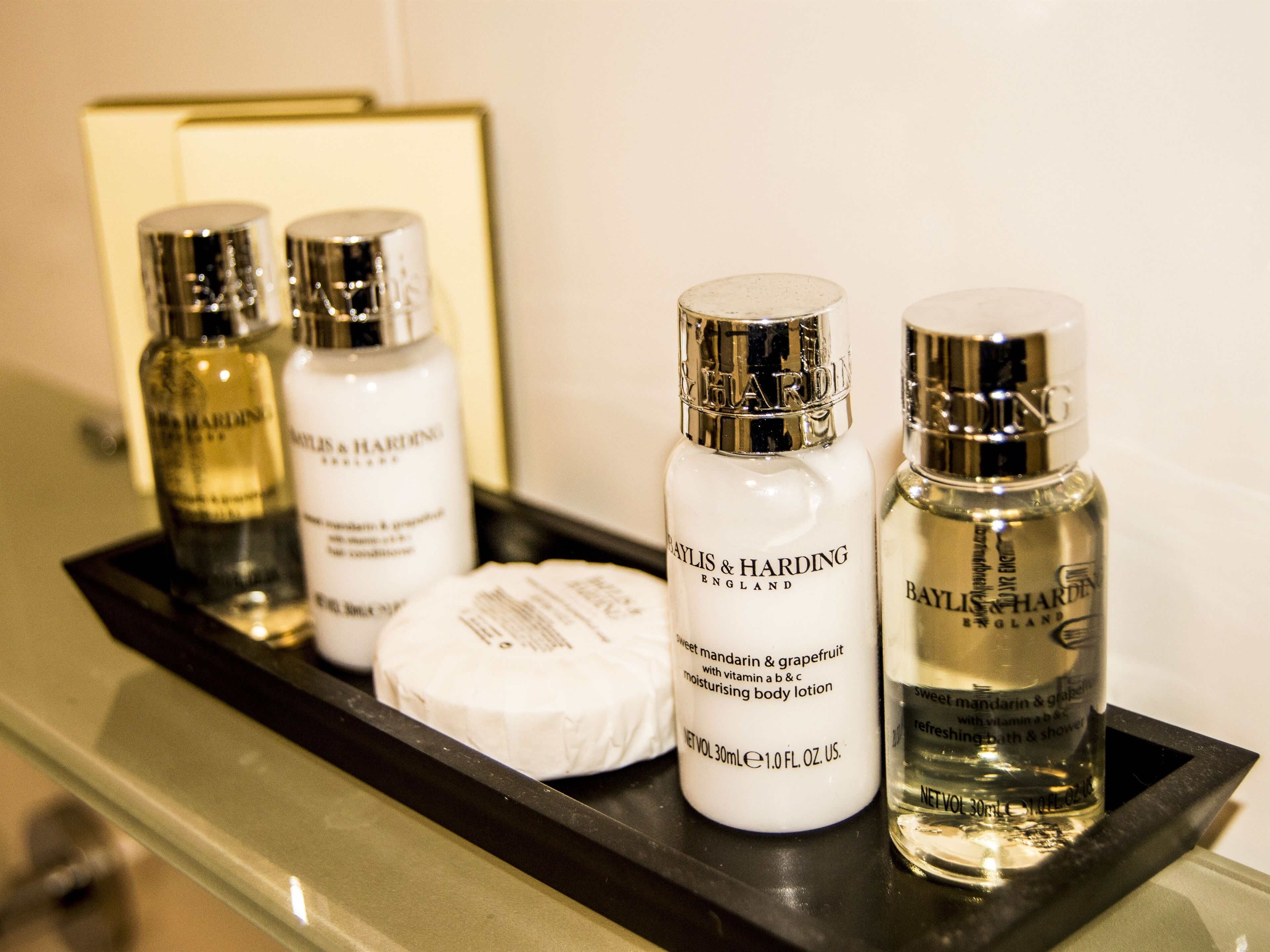 A tray with four bottles of Baylis & Harding body lotion and a bar of soap.