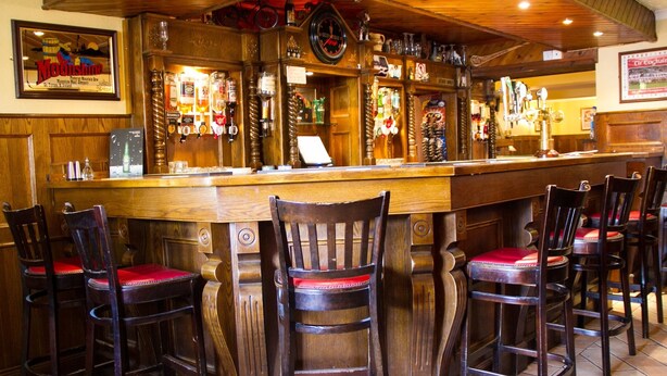A bar area with wooden bar stools, a clock, and various liquor bottles. - The Ryandale Inn (Dungannon)