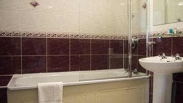 A bathroom with a bathtub, a glass shower enclosure, and a sink.