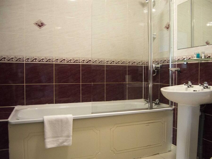 A bathroom with a bathtub, a glass shower enclosure, and a sink.