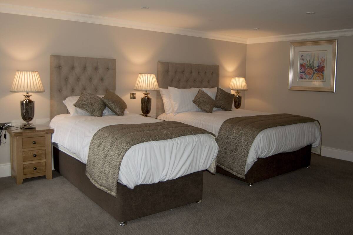 A double bed with a tufted headboard, two bedside tables with lamps, and a framed picture on the wall.