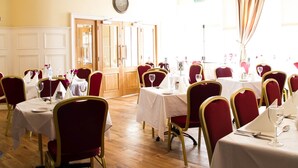 A dining area with tables set for six, wooden doors, a clock on the wall, and a glass ceiling. - The Ryandale Inn (Dungannon)