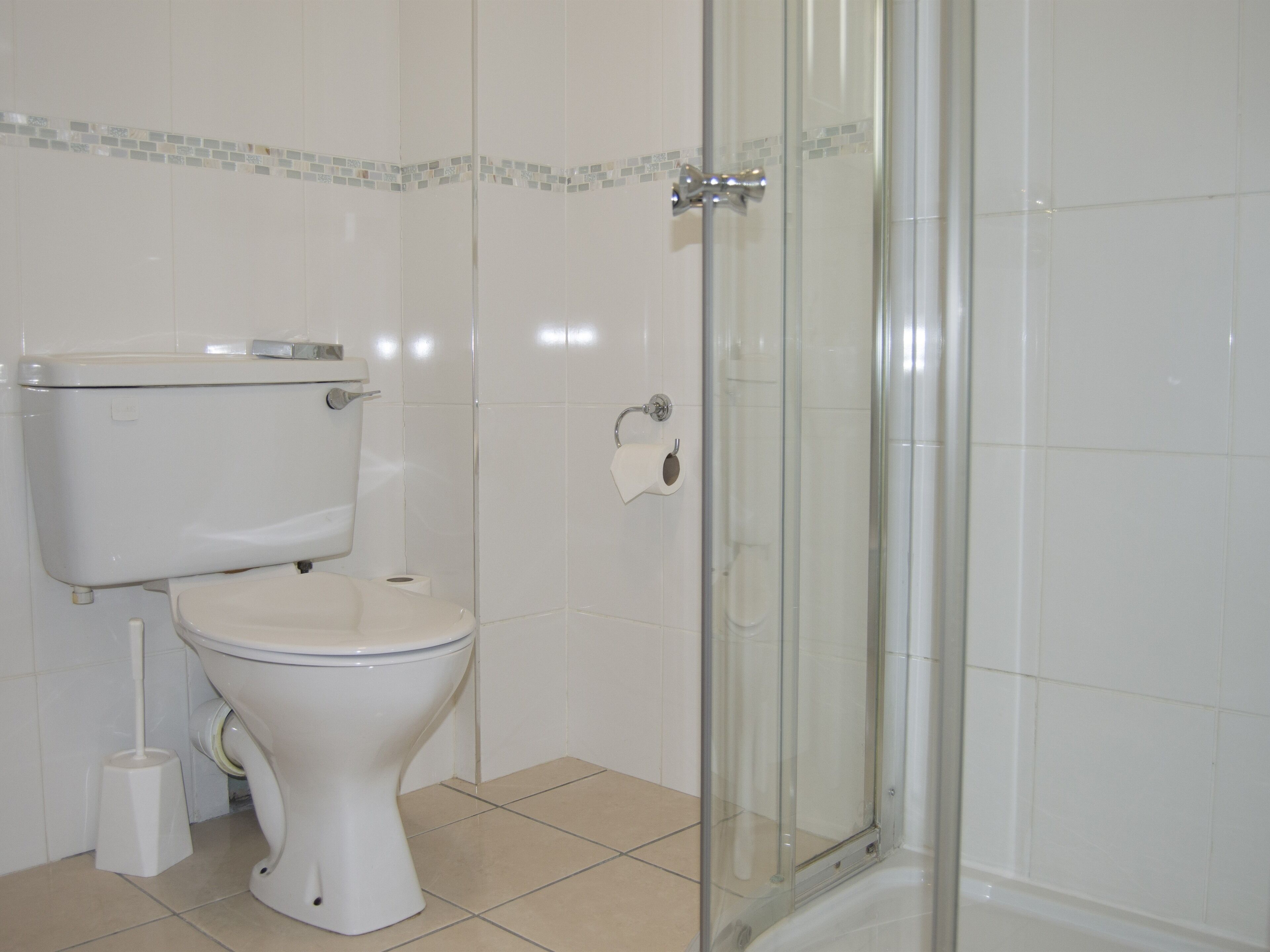 Ein Badezimmer mit Toilette, Duschkabine und Toilettenpapierhalter.