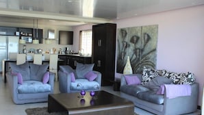 Uma sala de estar moderna com sofás cinza, uma mesa de centro de madeira e uma grande pintura abstrata.