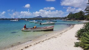 Une plage avec des bateaux, une eau cristalline et une montagne en arrière-plan.