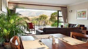 A dining area with a table set for four, a sofa, and a view of mountains through large windows.