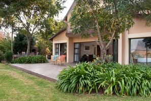 A modern two-story house with a patio, outdoor seating, and lush greenery. - Ama Casa Cottages (Cathkin Park)