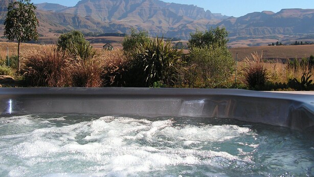 A hot tub with a view of mountains and dry grassland.
