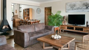 A living room with a brown leather sofa, a wooden coffee table with decorative items, a television, and a fireplace.