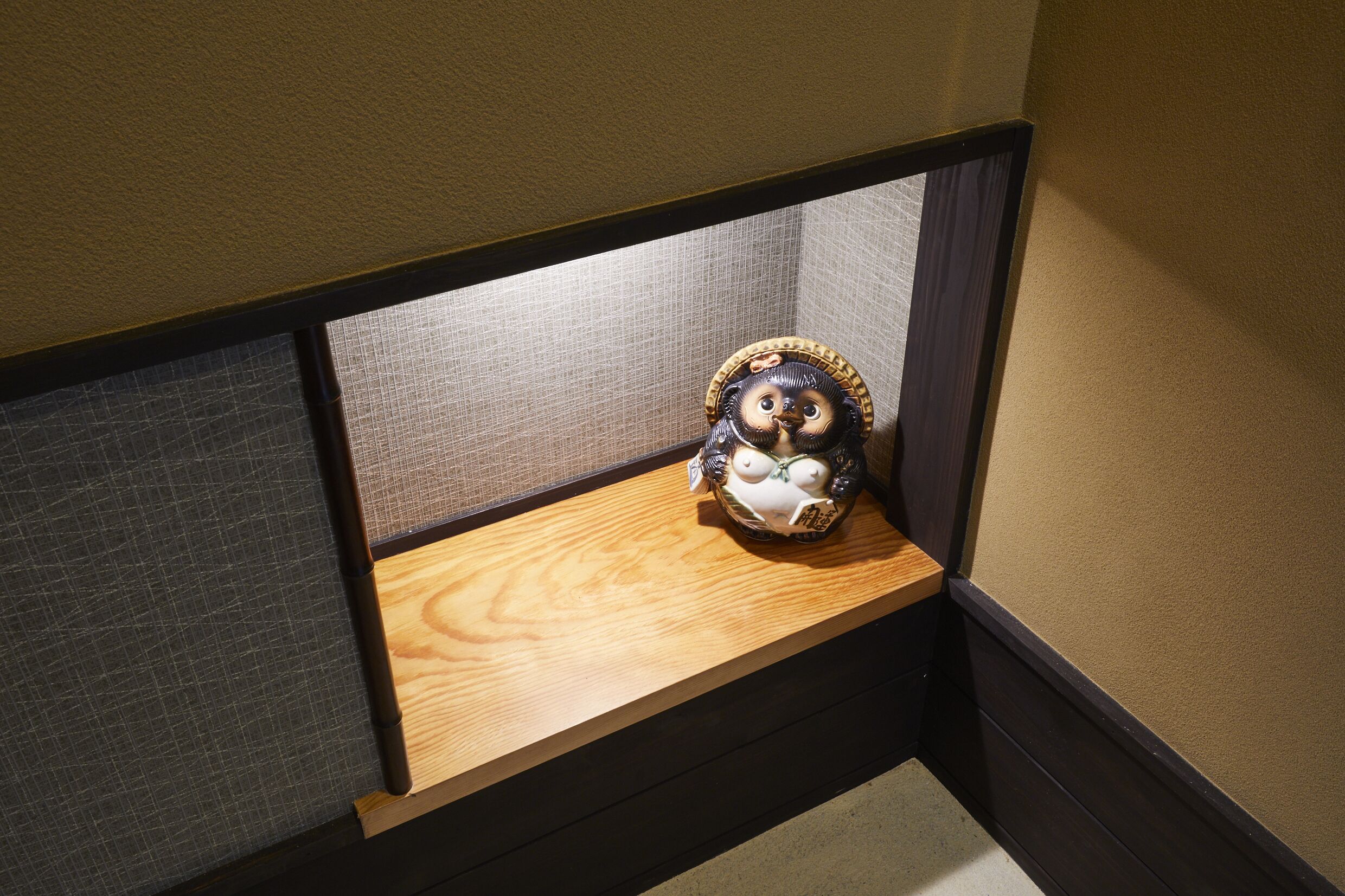A corner of a room with a wooden shelf and a decorative item.