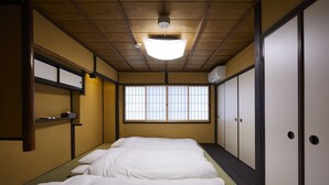 Een traditionele Japanse kamer met tatami vloeren, een futonbed, schuifdeuren en een plafondventilator.