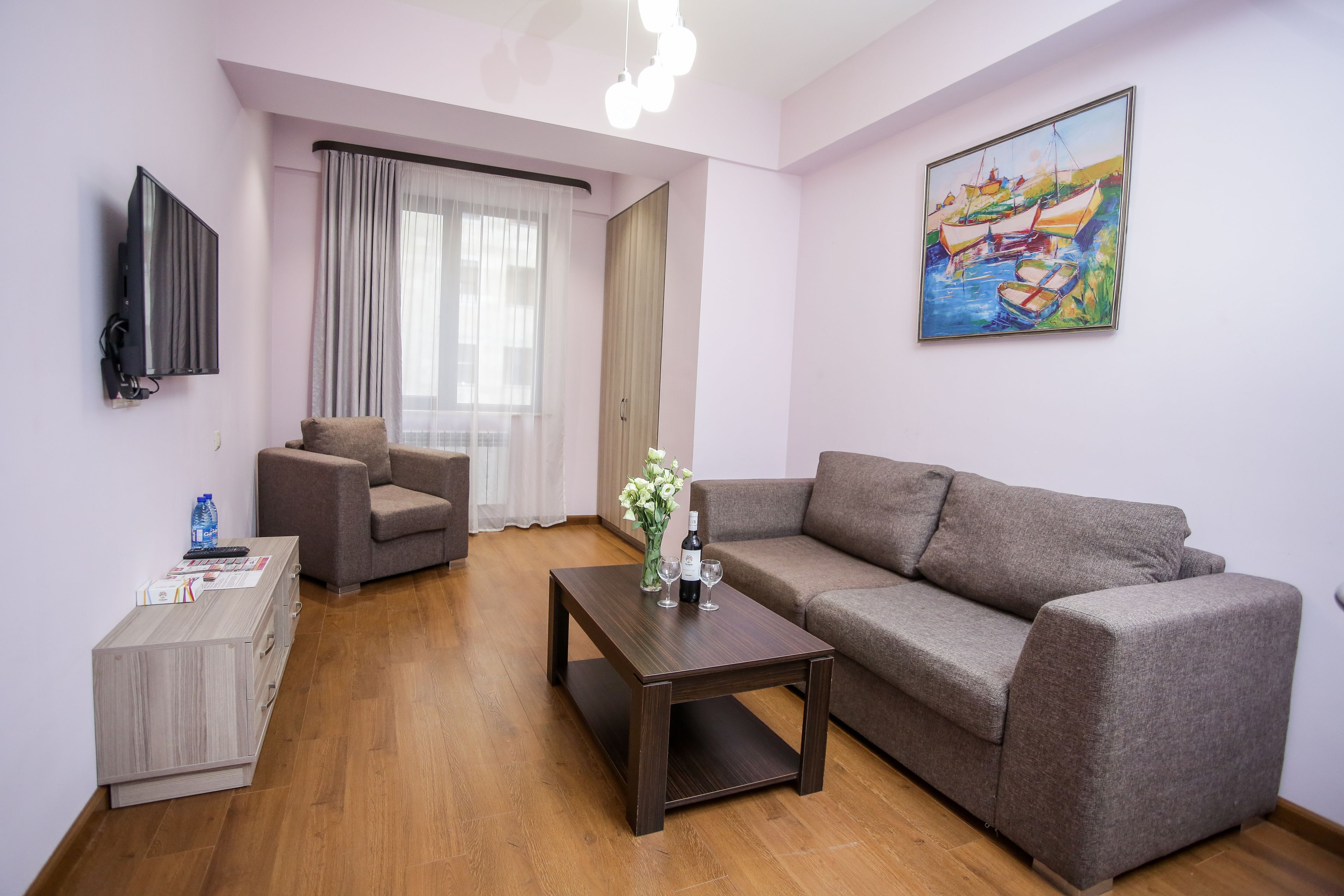 A living room with a sofa, a coffee table, a TV, and a painting on the wall.