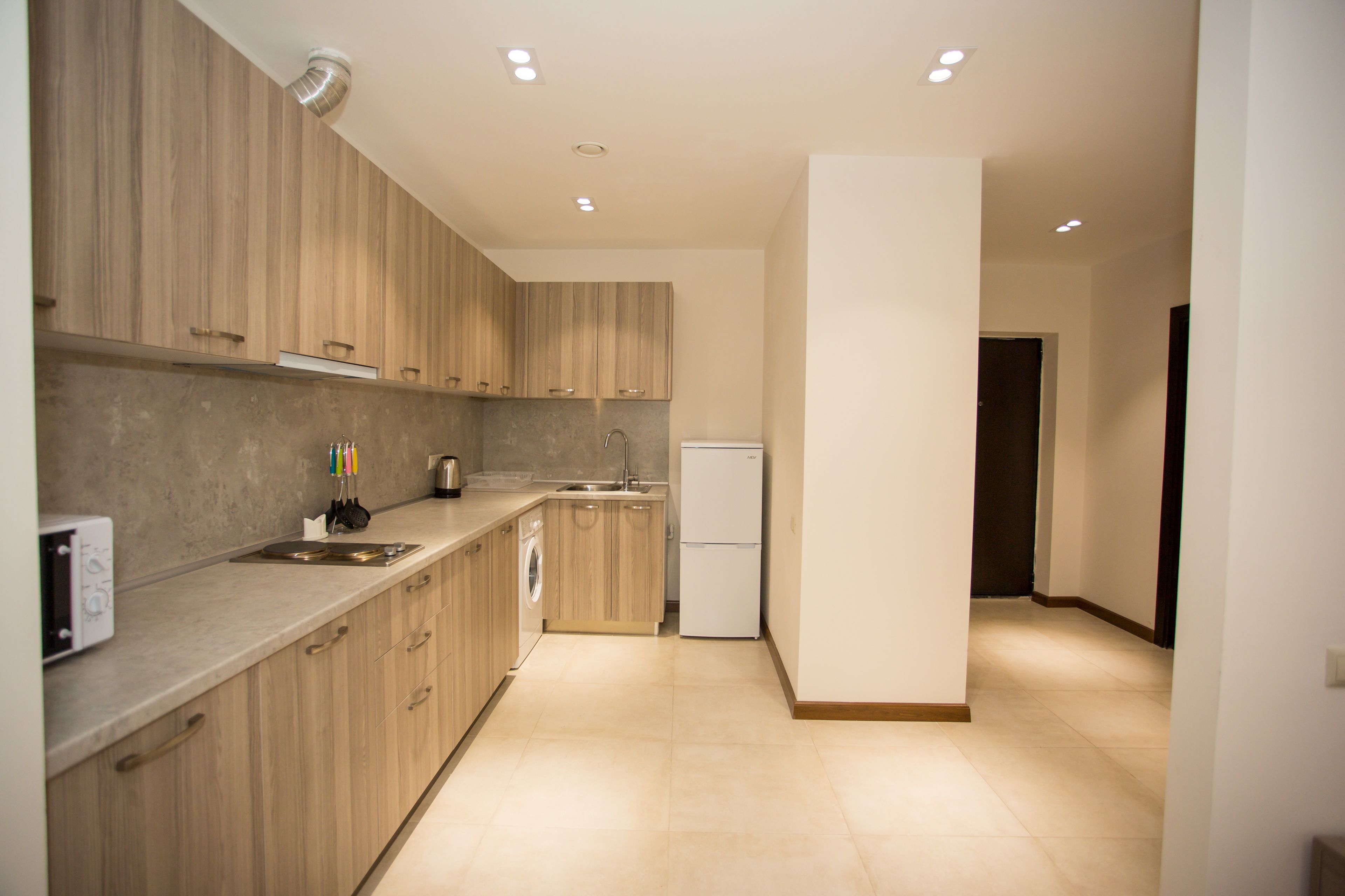 A modern kitchen with wooden cabinets, a built-in oven, a sink, and a refrigerator.