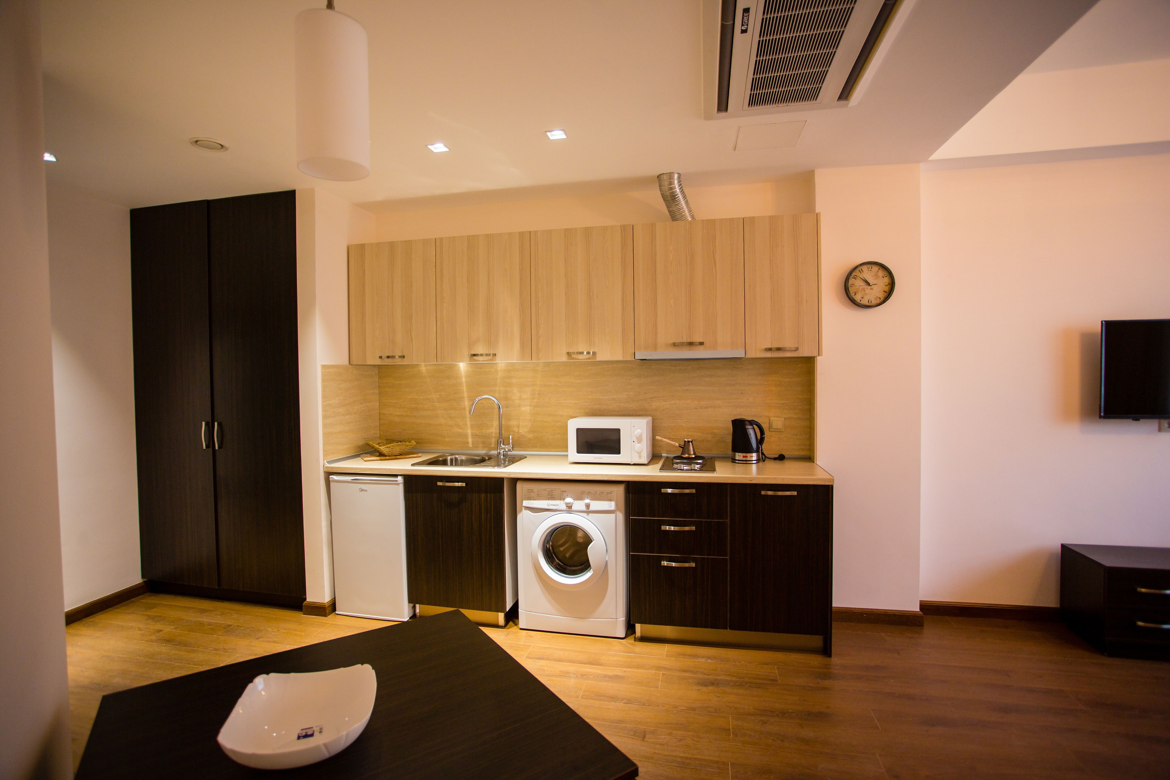 A compact kitchen with a microwave, sink, and washing machine.