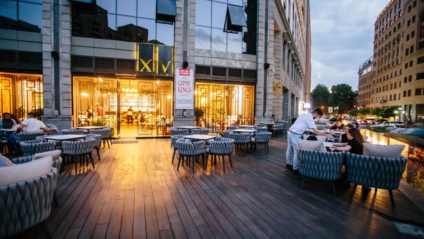 An outdoor seating area with tables and chairs in front of a building with a 'GIPSY KINGS' sign. - Welcome City Center Apartments (Yerevan)