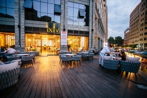 Un espacio al aire libre con mesas y sillas frente a un edificio con un letrero que dice 'GIPSY KINGS'.