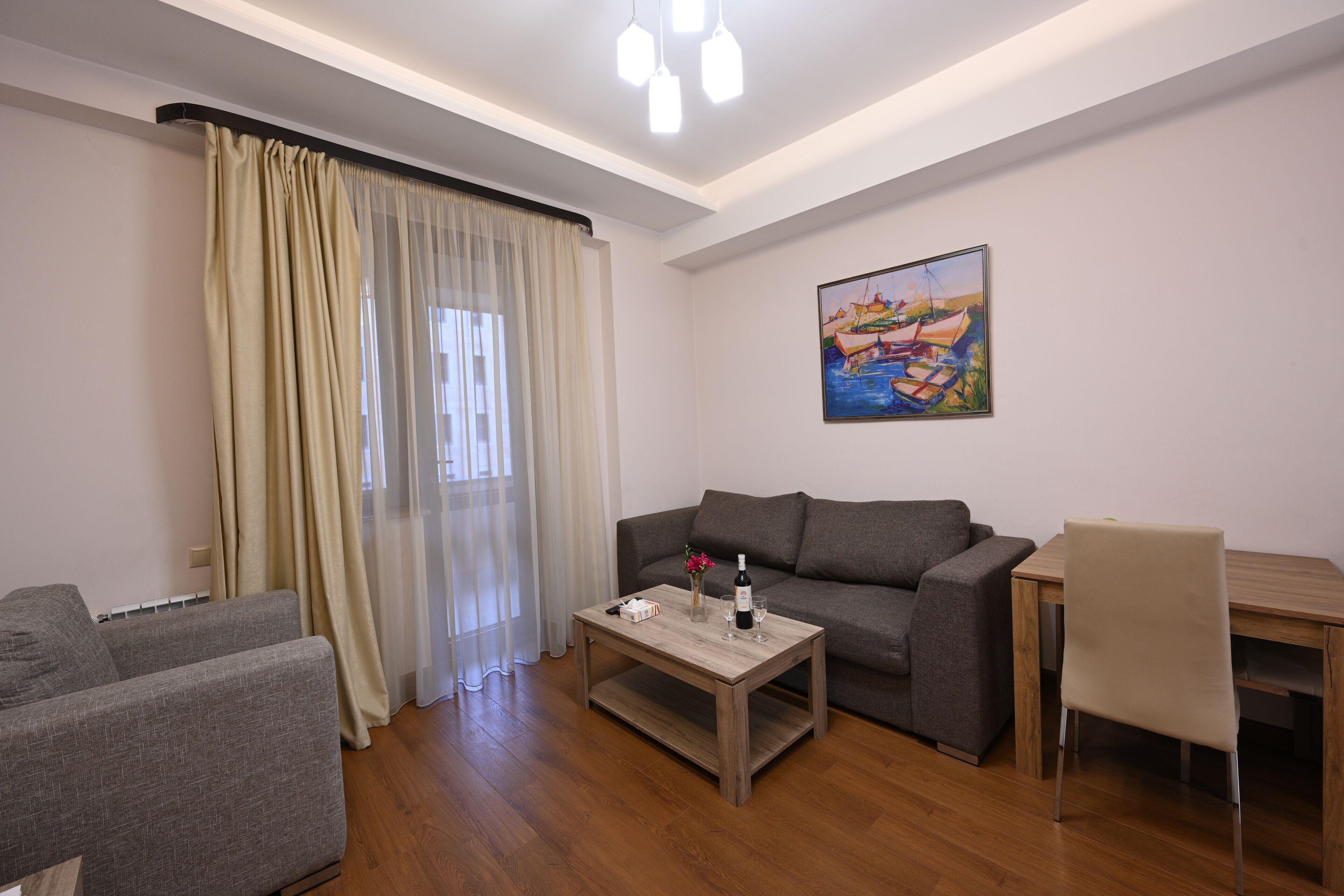 Un salon comprenant un canapé, une table basse, une table à manger avec une chaise, et un tableau accroché au mur.