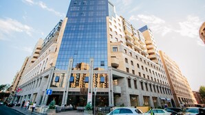A multi-story hotel with a modern glass facade, a ground-level cafe, and a visible entrance. - Welcome City Center Apartments (Yerevan)