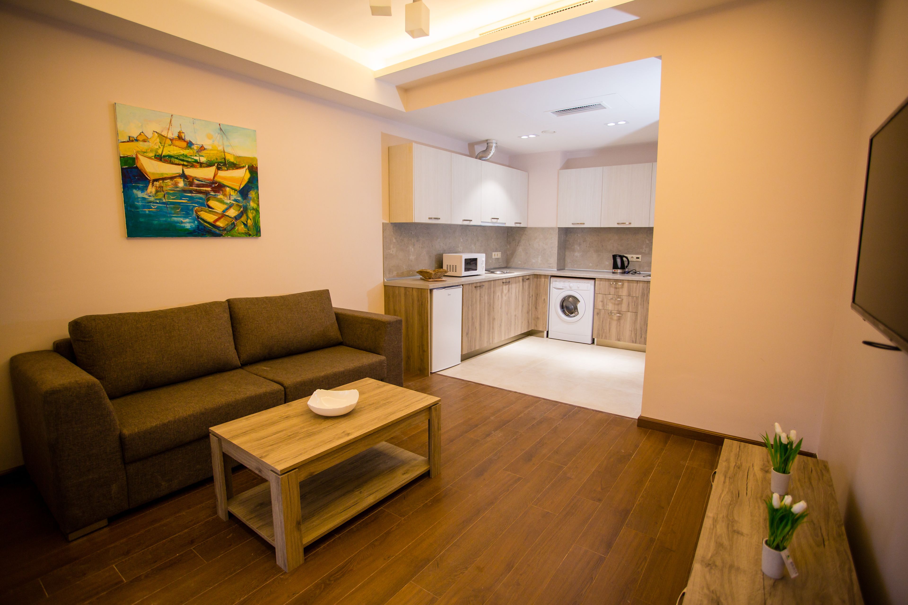 A modern living room with a sofa, a wooden coffee table, and a painting on the wall.