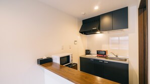 Una cocina compacta con microondas, cafetera y lavabo.