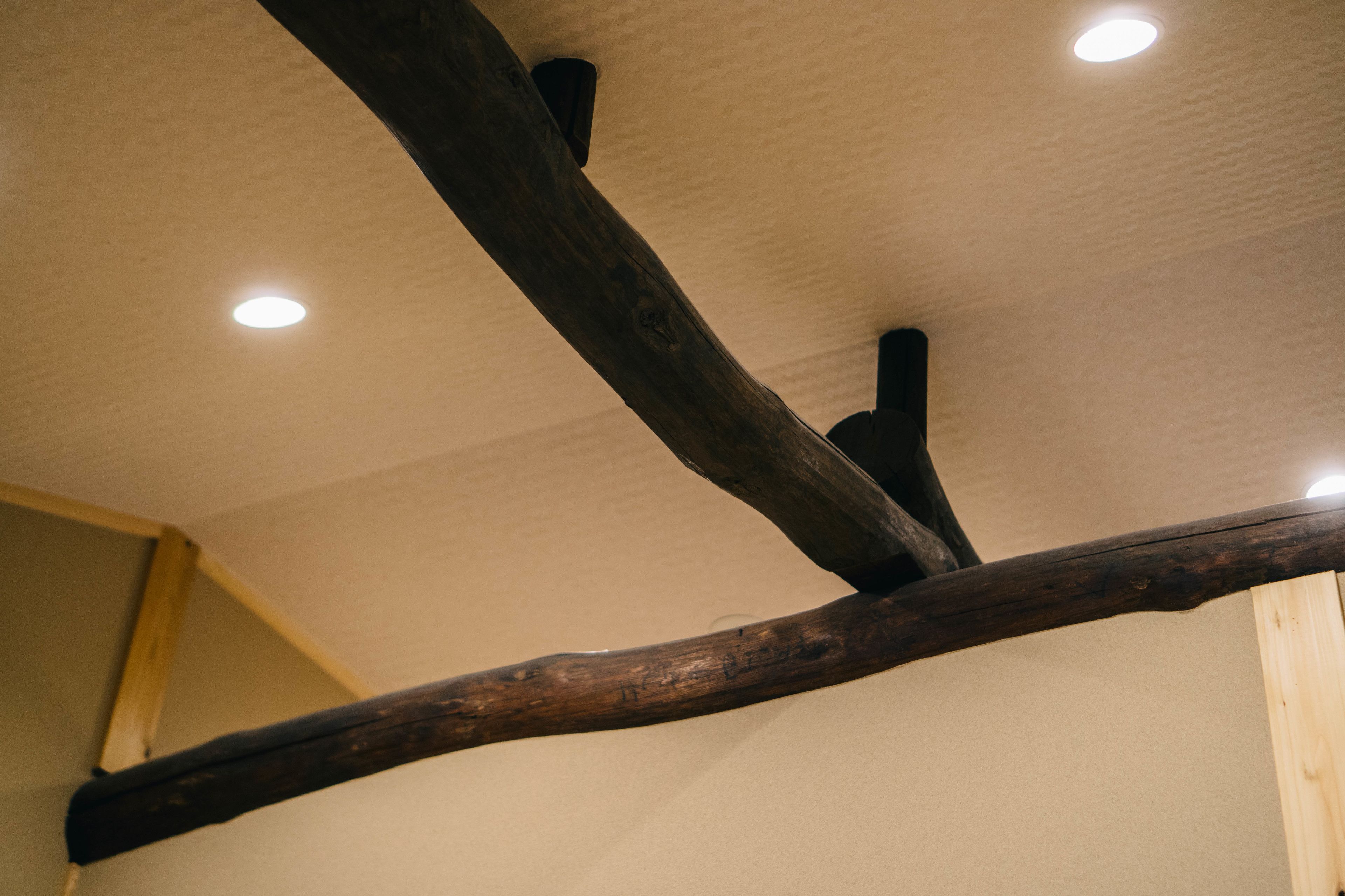 A ceiling with wooden beams and recessed lighting.